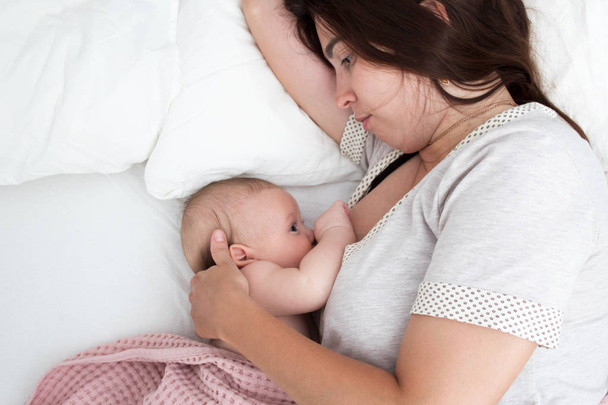 Brunette woman breastfeeds a baby. Mom with baby closeup - Zdjęcie, obraz