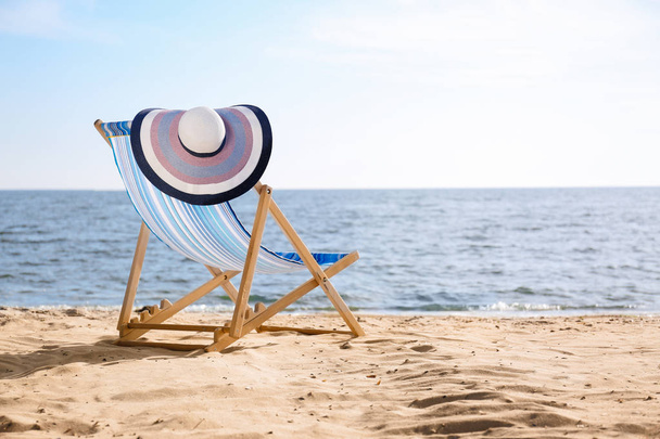 Lounger and hat on sand near sea, space for text. Beach objects - Foto, Imagem