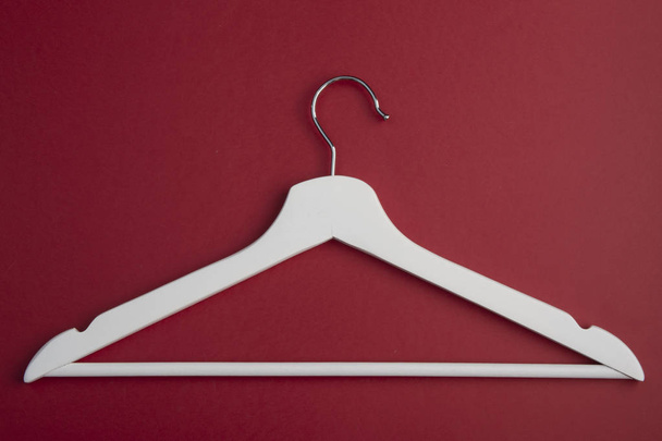 White wooden clother hanger isolated on red background. Fasion concept. Sale clother. Flat lay - Fotó, kép