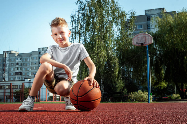 Portrait of a boy with a basketball on a basketball court. The concept of a sports lifestyle, training, sport, leisure, vacation. - Foto, immagini