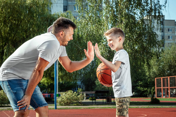 Father and son play basketball together at the basketball court. father spends time with the child, sporty lifestyle, training, rest, vacation. - Zdjęcie, obraz