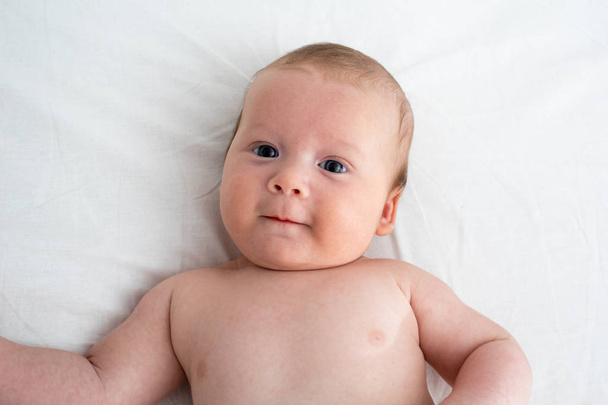 Happy baby lying on a white blanket. The concept of purity and j - Fotoğraf, Görsel