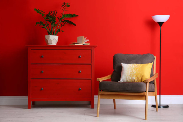 Stylish room interior with modern furniture and houseplant near red wall - Zdjęcie, obraz