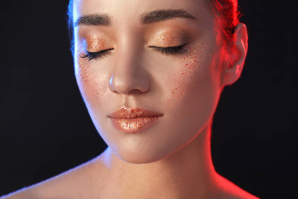 Beautiful young woman with glitter makeup on black background - Foto, imagen