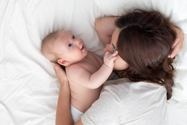 Beautiful brunette girl hugs and plays with baby. The concept of - Φωτογραφία, εικόνα
