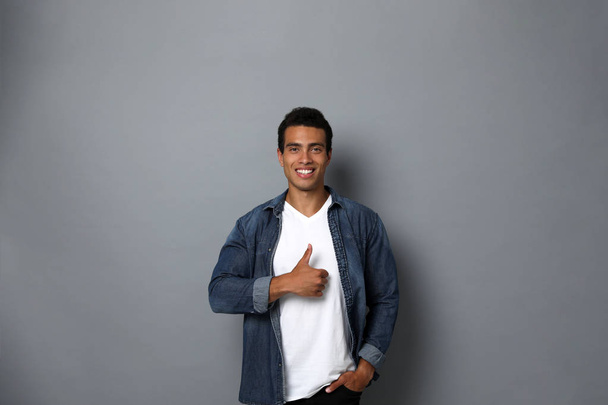 Handsome young African-American man showing thumbs-up gesture on grey background - Foto, Imagem