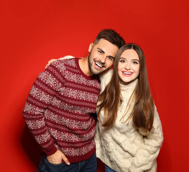 Couple wearing Christmas sweaters on red background - Foto, Bild