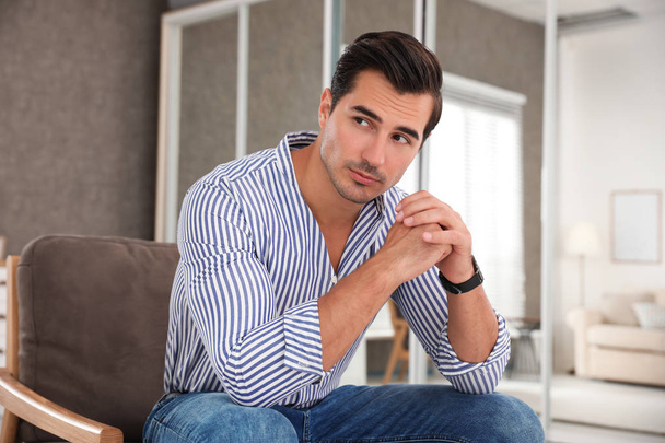 Portrait on handsome young man sitting in chair indoors - Foto, Bild