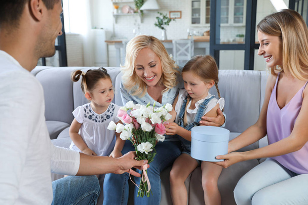 Happy family with little children congratulating mature woman in living room - Foto, immagini