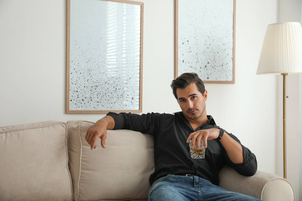 Young man with glass of whiskey at home - Φωτογραφία, εικόνα
