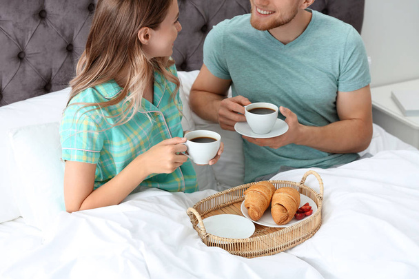 Happy young couple having romantic breakfast in bed at home - Foto, Imagen