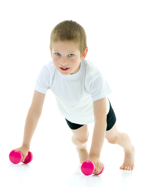 A little boy is lifting dumbbells. - Photo, image