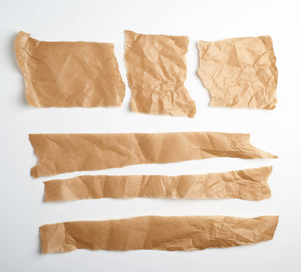 разорванные коричневые кусочки пергаментной бумаги на белом фоне - Фото, изображение