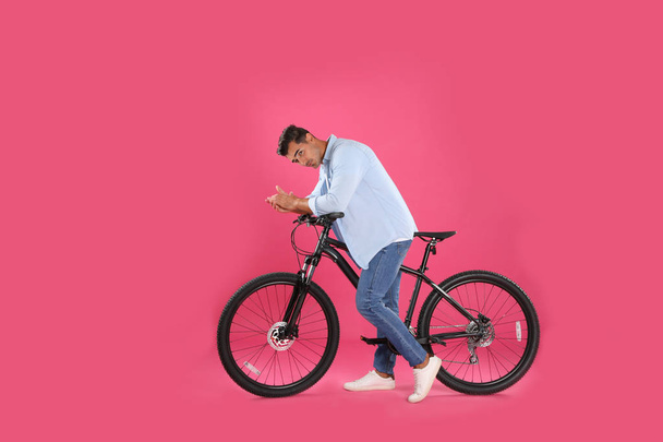 Handsome young man with modern bicycle on pink background - 写真・画像