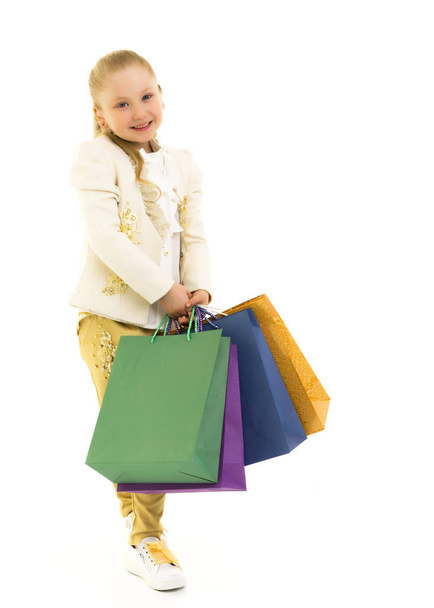 Little girl with multi-colored bags in their hands. - 写真・画像