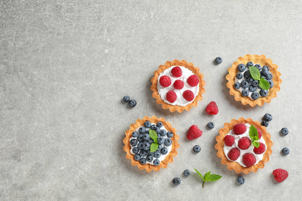 Delicious sweet pastries with berries on grey table, flat lay. Space for text - Foto, Imagen