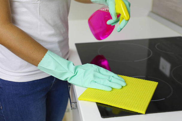 Femme mains nettoyer une plaque à induction noire moderne par un chiffon et pulvérisation
. - Photo, image