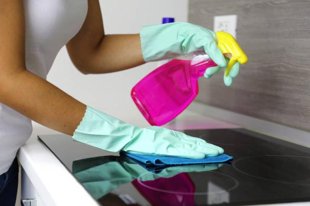 Nainen puhdistaa moderni musta induktio liesi rätti ja spray
. - Valokuva, kuva