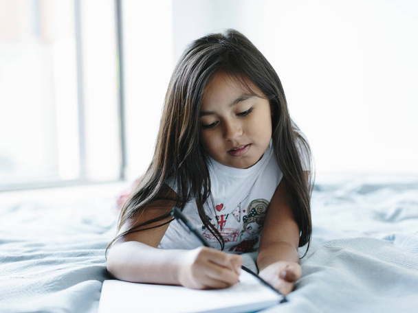 Fiatal lány feküdt az ágyon írt egy notebook-on - Fotó, kép