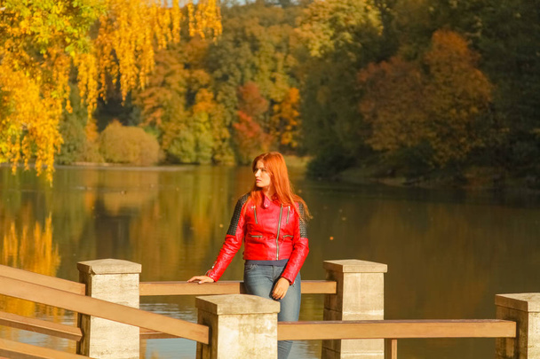 Młody ładny plus rozmiar kaukaski kobieta spacery w pobliżu jeziora w jesiennym parku - Zdjęcie, obraz