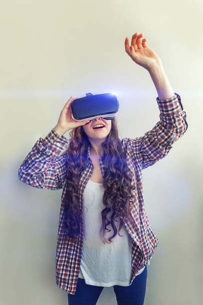 Sonríe mujer joven usando realidad virtual gafas VR casco auriculares sobre fondo blanco. Smartphone con gafas de realidad virtual
 - Foto, imagen