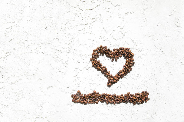 Heart of coffee beans on a white textured background. The concept of good morning. - Foto, imagen