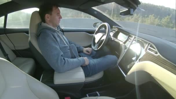 TESLA AUTONOMOUS CAR, March 2018 - CLOSE UP, LENS FLARE: Carefree man drives down a sunny highway in a Tesla autonomous car. Relaxed young male driving along the road in a computer controlled vehicle - Imágenes, Vídeo