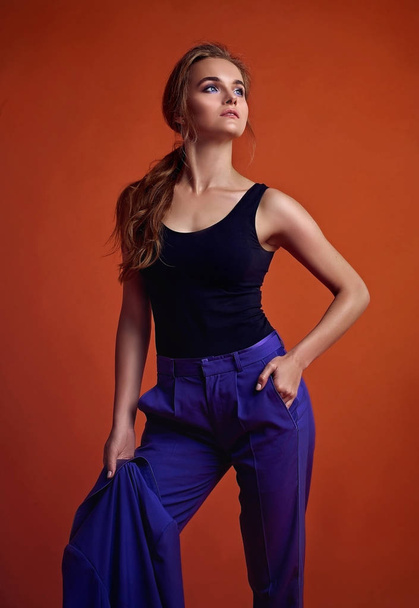 Young attractive women model , wearing purple suit , posing in studio.Orange background. - Foto, Bild