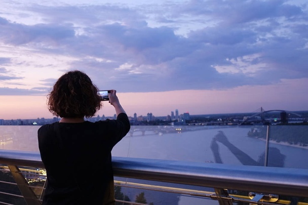 mulher fotografa o pôr do sol no Dnieper
                - Foto, Imagem