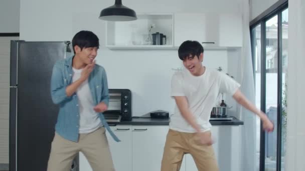 Asian Gay couple dancing at home. Young Asian LGBTQ men feeling happy fun dance, singing, listening music while in kitchen at home concept. Slow motion Shot. - Séquence, vidéo