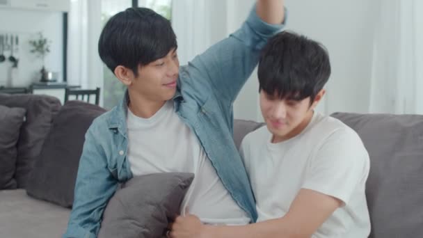 Young Asian Gay couple hug and kiss at home. Attractive Asian LGBTQ pride men happy relax spend romantic time together while lying sofa in living room concept. Slow motion Shot. - Footage, Video