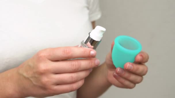womans hand uses lubricant to lubricate the menstrual cup intimate personal hygiene product for a comfortable installation during period time - Video, Çekim
