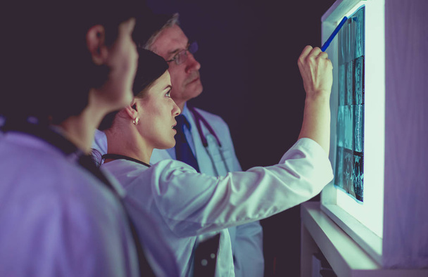 Группа врачей, осматривающих рентгеновские снимки в клинике, размышляющих над диагнозом - Фото, изображение