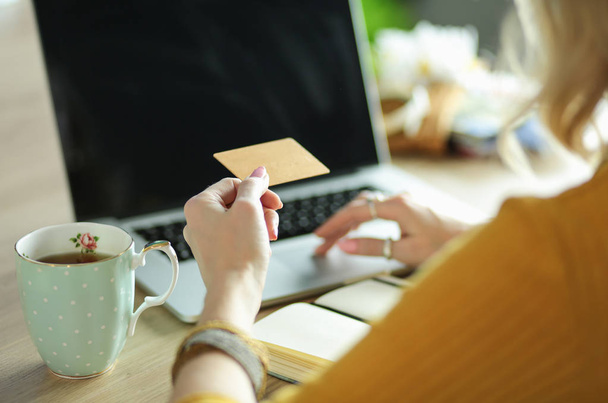 Young woman holding credit card and using laptop computer. Online shopping concept - Foto, Bild