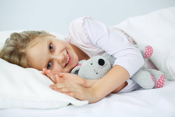 Child little girl sleeps in the bed with a toy teddy bear. - Fotoğraf, Görsel