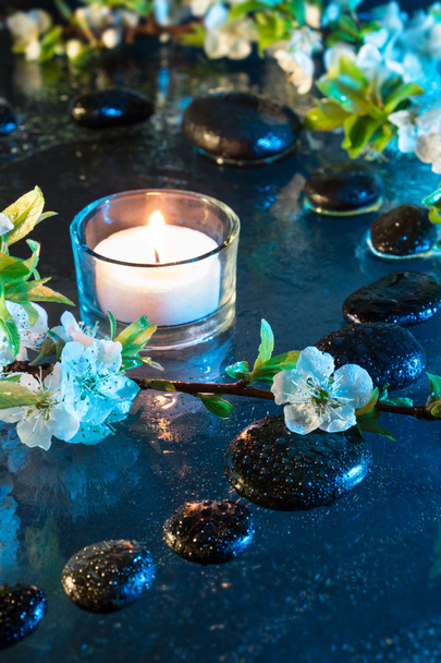 Almond flowers with black stones and candle - Photo, Image