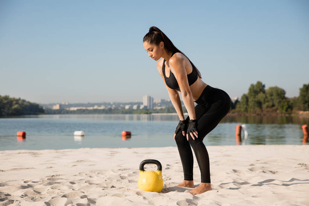 Young healthy female athlete doing workout at the beach - 写真・画像
