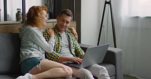Щаслива пара в повсякденному одязі, розслабляється на дивані, використовуючи ноутбук
 - Кадри, відео