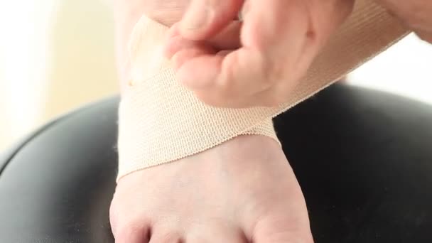 Ένας ανώτερος άνθρωπος βάζει ένα ελαστικό τυλίγει γύρω από το πονεμένο πόδι του - Πλάνα, βίντεο