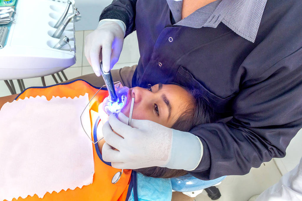 Dentista colocando aparatos ortopédicos en una adolescente con instrumentos de alta tecnología
 - Foto, Imagen