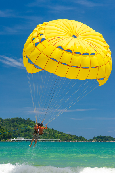 Slunečiště je populární vodní sport na pláži Patong, Thajsko. Lidé letící na barevný padák vlečený rychlými čluny s jasnou modrou oblohou na pozadí. Pobavení vody. - Fotografie, Obrázek