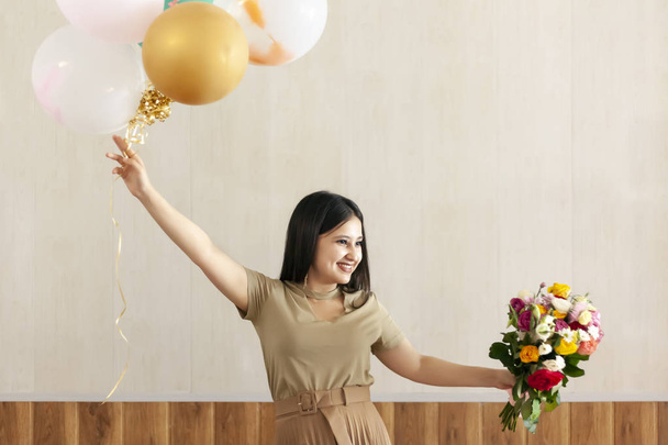 Portré bájos, csinos lány gazdaság csokor virágok és hőlégballonok - Fotó, kép