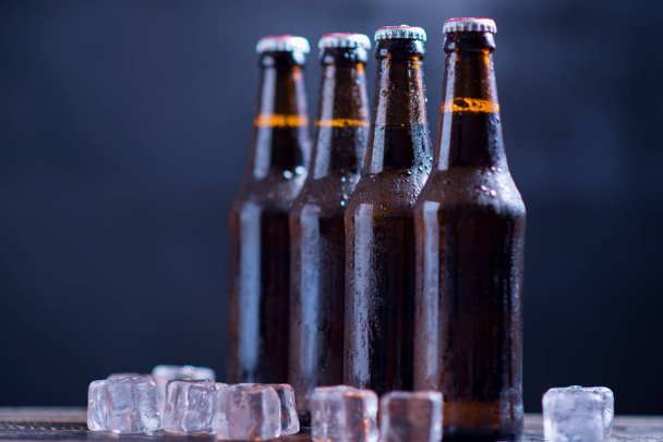 Nahaufnahme Glasflaschen Bier mit Eis auf dunklem Hintergrund - Foto, Bild