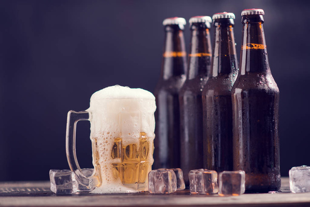 Glass bottles of beer with glass and ice on dark background - Foto, Imagem