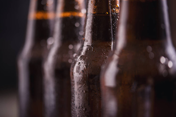 Nahaufnahme Glasflaschen Bier mit Eis auf dunklem Hintergrund - Foto, Bild