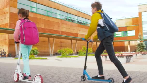 happy school children with backpacks and scooters - Metraje, vídeo