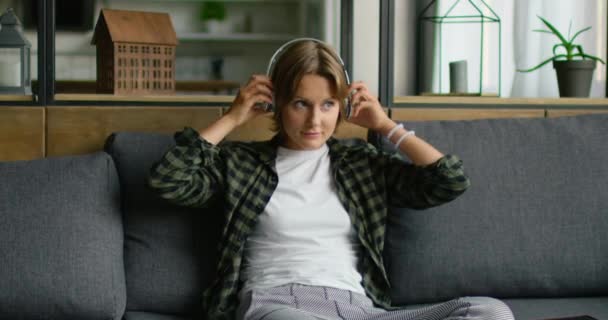 Young woman is putting wireless headset on, using tablet computer - Materiał filmowy, wideo