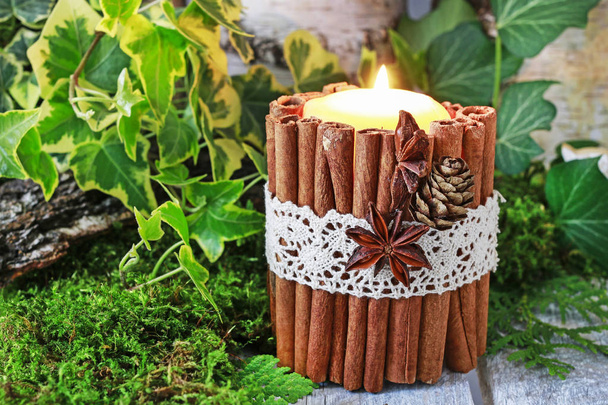 Candle decorated with cinnamon sticks, moss, ivy leaves - Foto, afbeelding