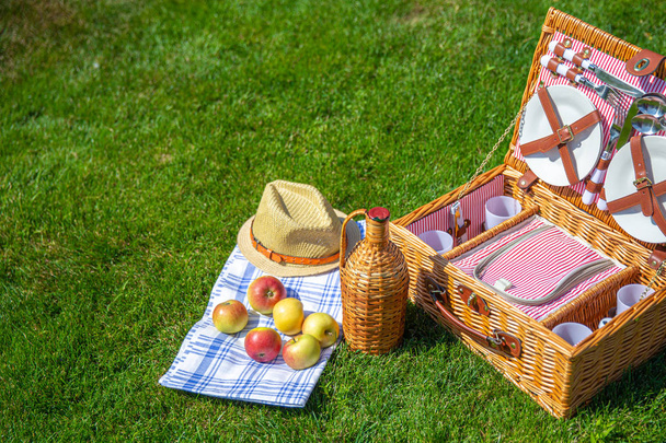 Picnic basket on green sunny lawn in the park - Photo, Image