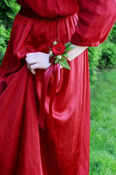 Bridesmaid wearing wrist corsage made of red rose flowers.  - Фото, изображение